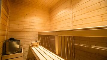 Una sauna de fusta amb seients i un recipient metàl·lic, probablement per aigua o vapor.