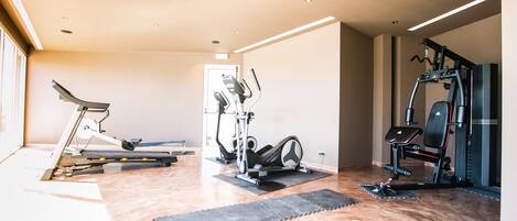 A modern home gym with exercise equipment, including a treadmill, elliptical, and weight machines.