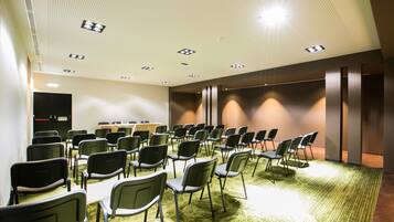 A conference room with rows of chairs, a podium, and a carpeted floor.