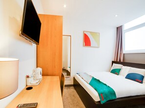A hotel room with a bed, a desk, a TV, a coffee machine, and a painting on the wall. - Snooze Hotel (Corby)