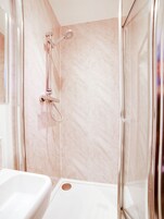 Un baño moderno con cabina de ducha de vidrio, una bañera blanca y paredes de mármol.