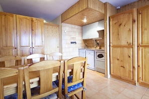 A wooden-paneled kitchen with a dining table and chairs, a built-in oven, and a sink.