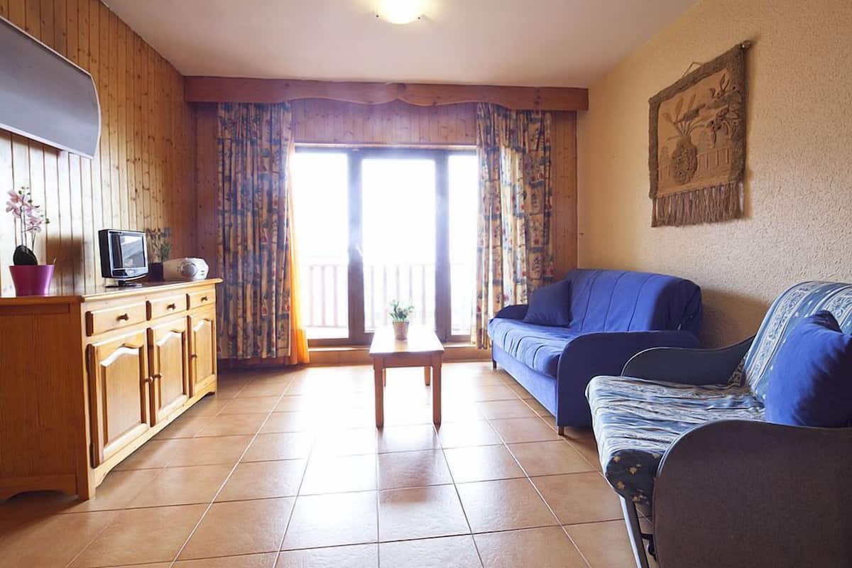 Una sala de estar con un mueble de madera, un televisor, un sofá y una mesa.