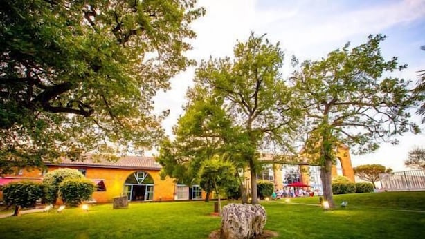 A courtyard with a building, trees, and a well-maintained lawn. - Les Ecuries de la Tour (Mondonville)