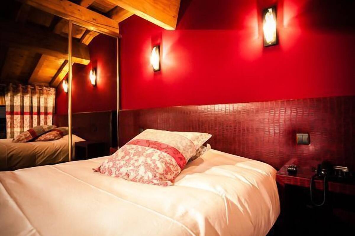 Un dormitorio con una cama grande, paredes rojas y techo de madera.