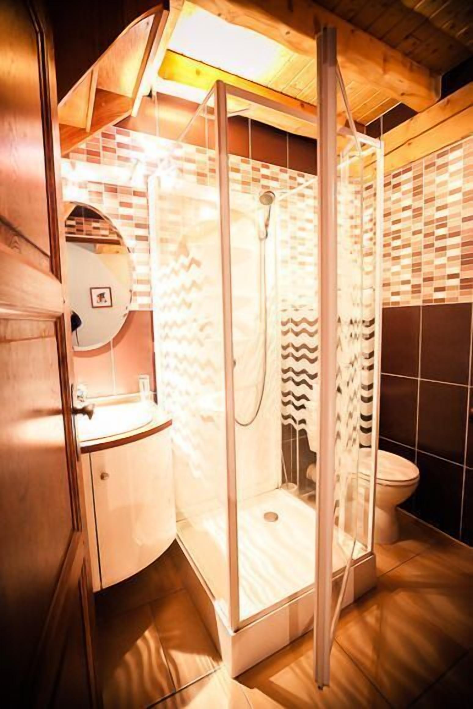 Ein modernes Badezimmer mit einer gläsernen Duschkabine, einem Holzausziehtisch und einem Spiegel.