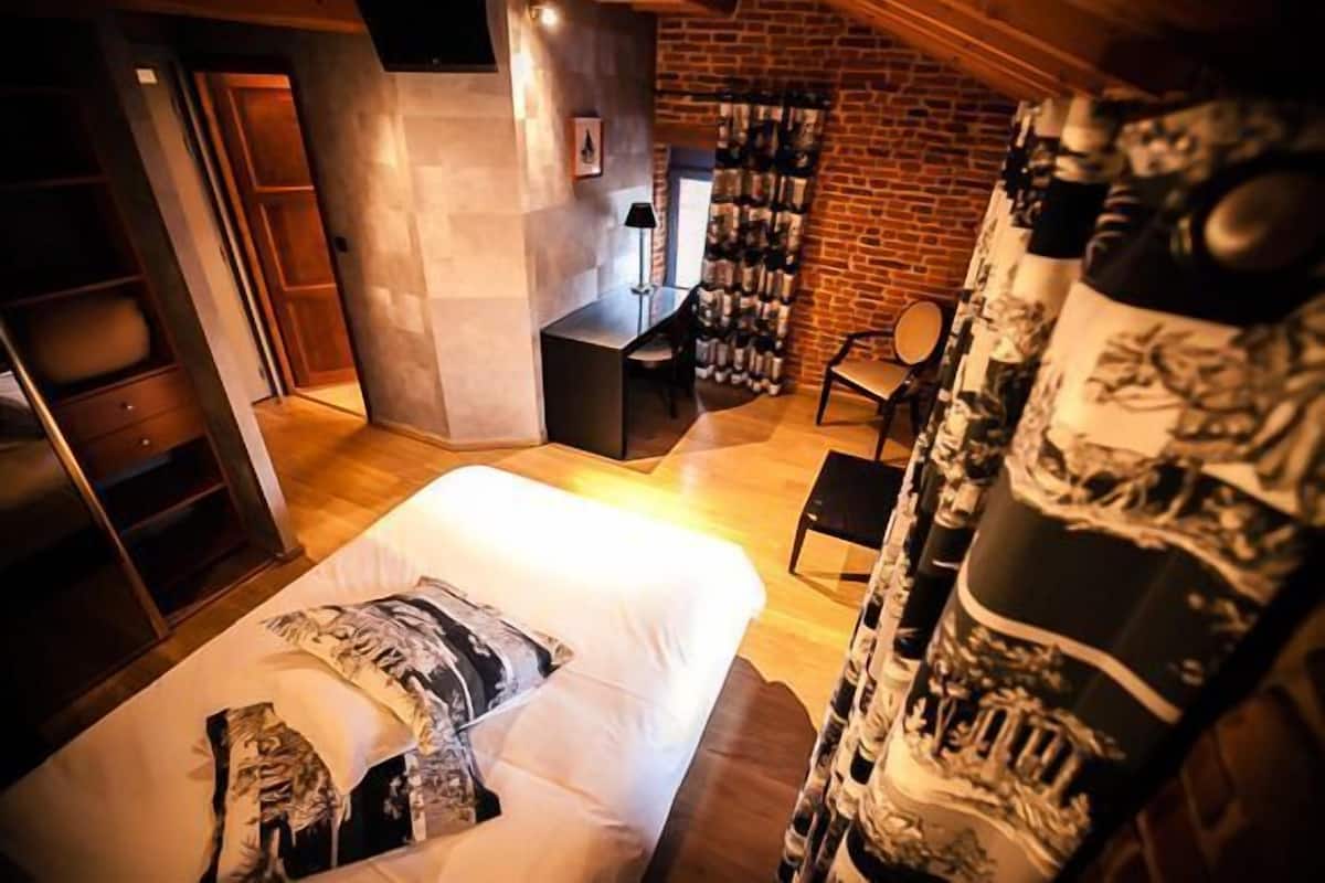 Un dormitorio con una cama, un escritorio y una pared de ladrillo.