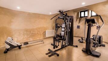 A gym with various exercise equipment, including a Kettler machine, a stair climber, and a treadmill.