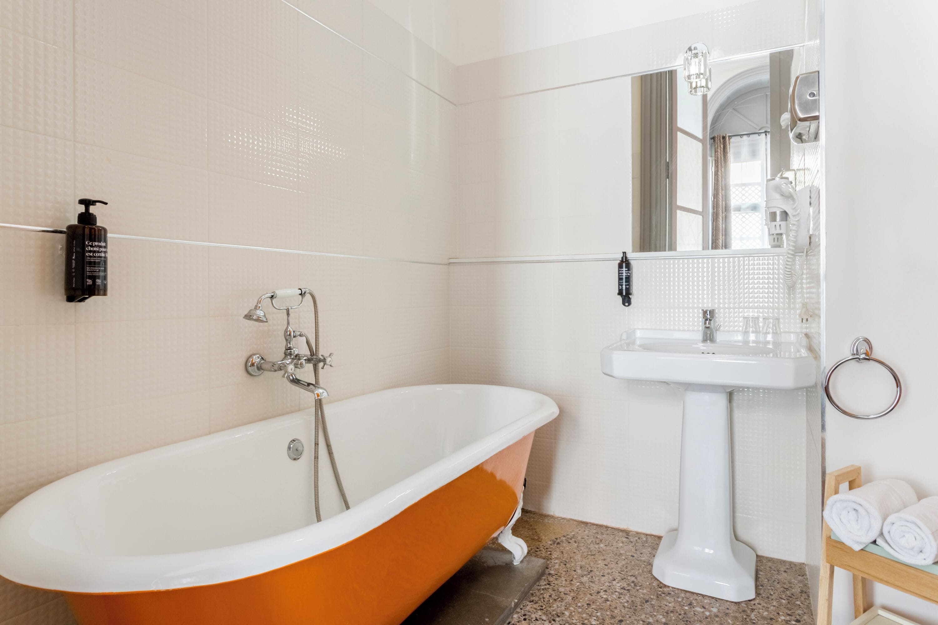 A bathroom with a white sink, a mirror, a towel rack, and a bathtub.