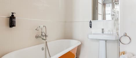 A bathroom with a white sink, a mirror, a towel rack, and a bathtub.