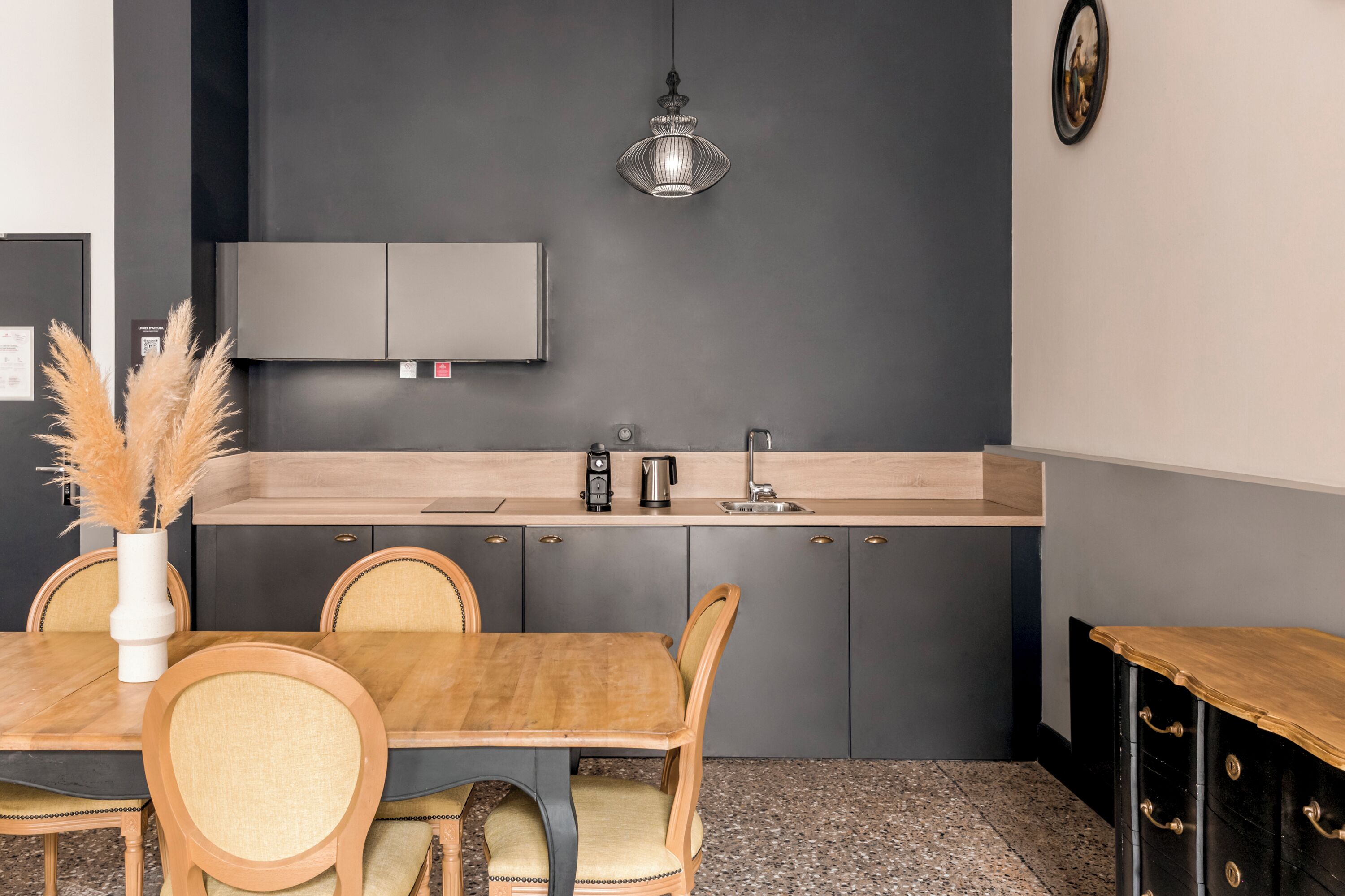 A compact kitchen with a dark wall, a wooden dining table, and chairs.