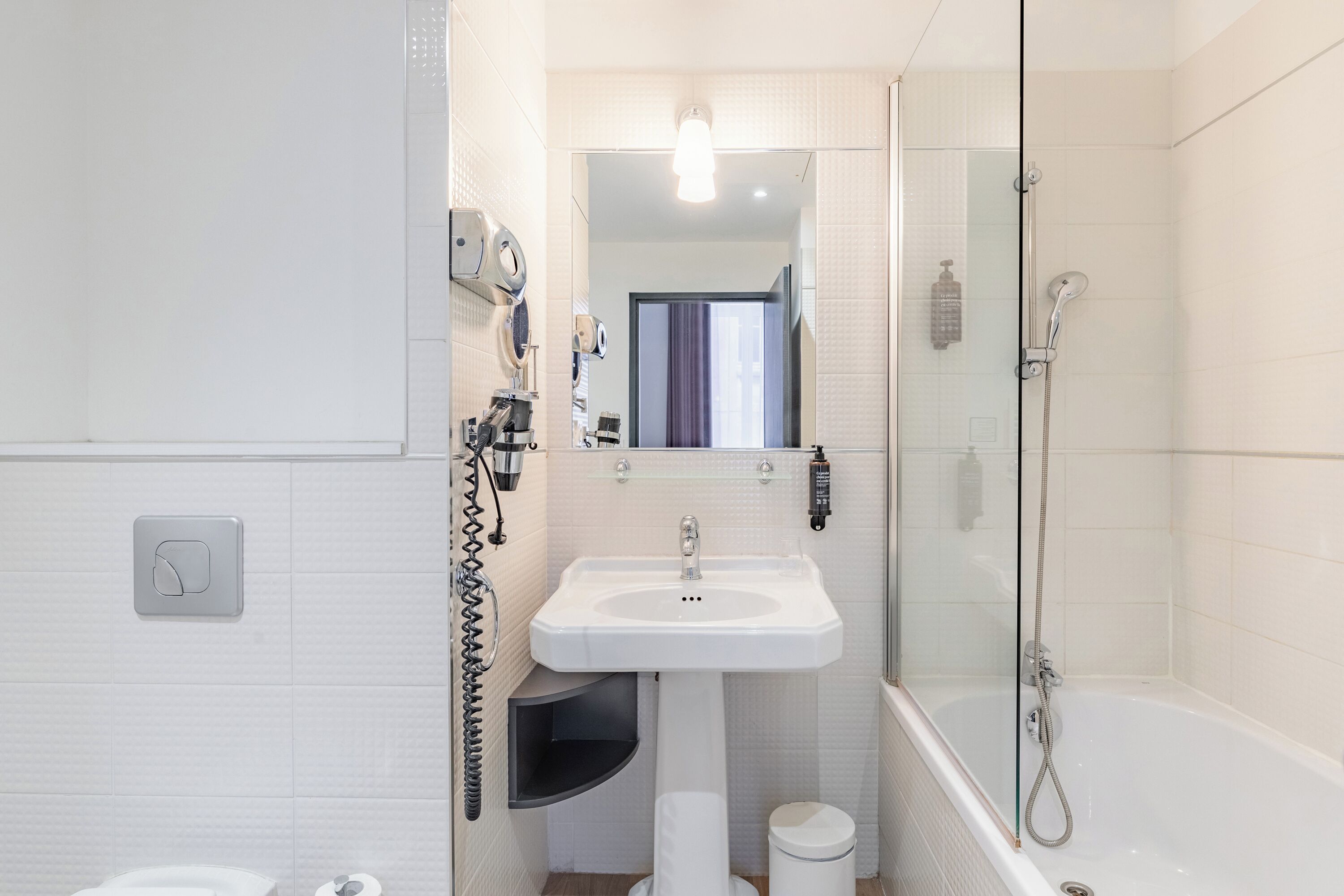 A modern bathroom with a glass-enclosed shower, a pedestal sink, and a toilet.