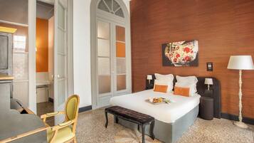 A hotel room with a bed, bedside lamps, a bench, a desk, and a chair.