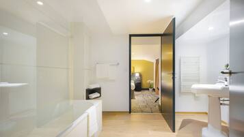 Een moderne badkamer met een douchecabine van glas, een bad, een toilet en een wastafel.