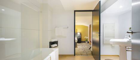 A modern bathroom with a glass shower enclosure, a bathtub, a toilet, and a sink.