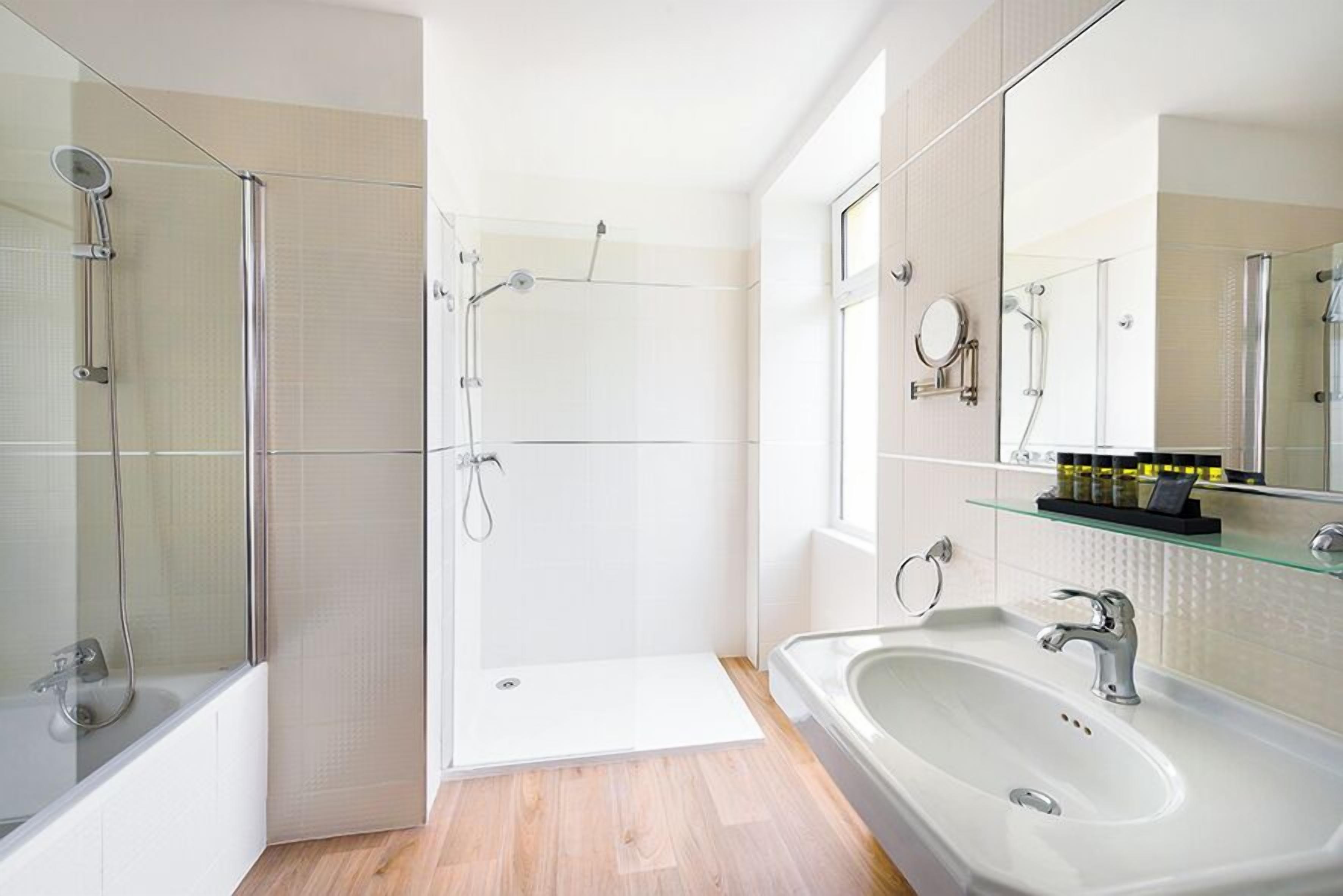 Een moderne badkamer met een glazen douchecabine, een vrijstaand bad, een wastafelmeubel met een grote spiegel en een glazen plank met toiletartikelen.