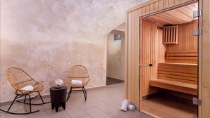 Un cuarto de spa con dos sillones de mimbre, una mesita con un objeto decorativo y una sauna de madera.