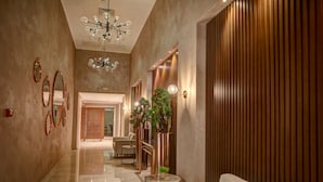 A hallway with a chandelier, mirrors, a sofa, and a staircase with plants. - Hôtel Lac Léman, LES BERGES DU LAC (Tunis)