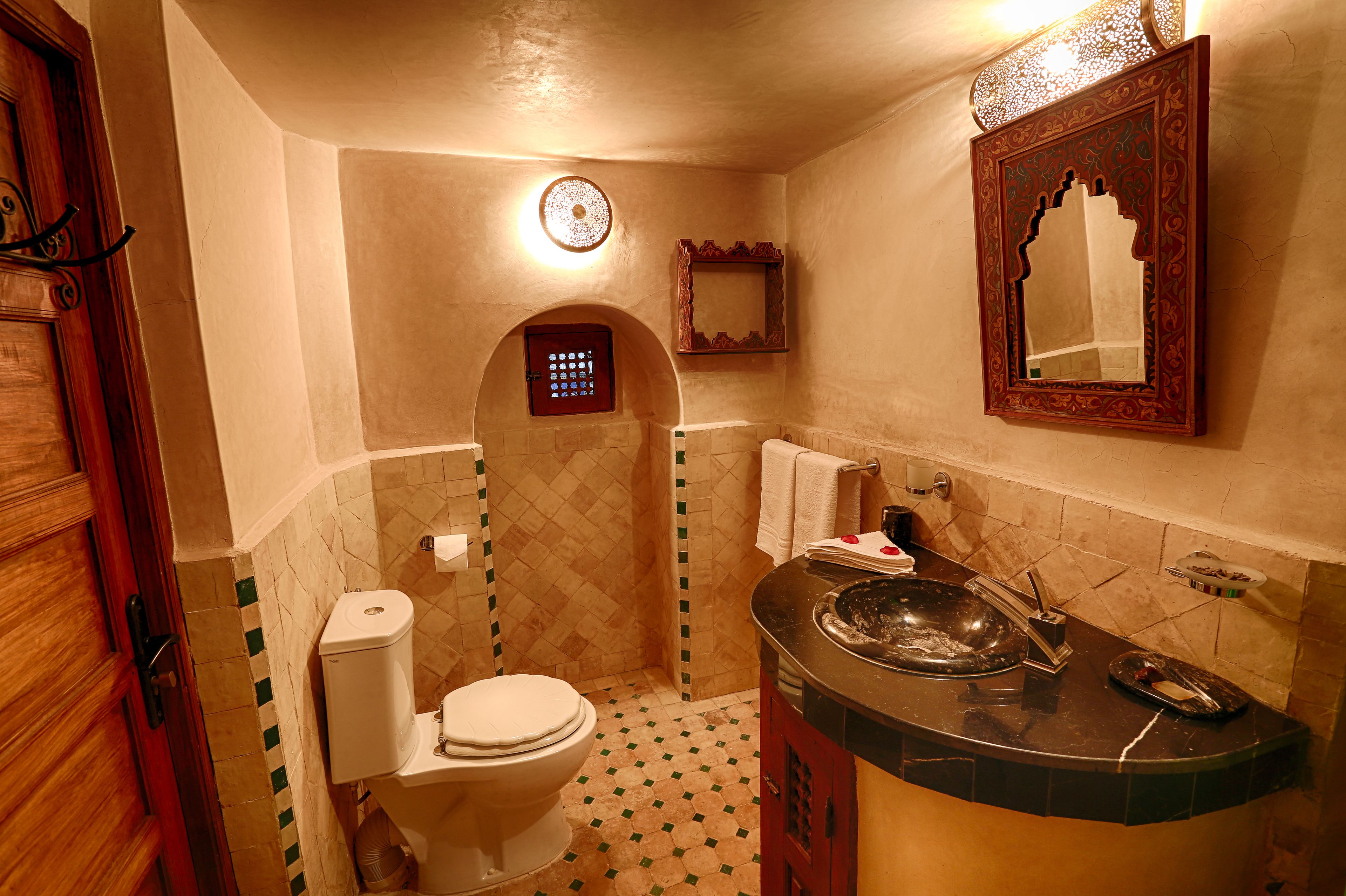 A bathroom with a toilet, sink, and mirror.