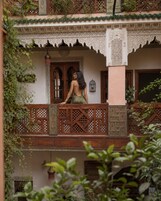 Varanda com detalhada treliça de madeira e uma pessoa de pé.