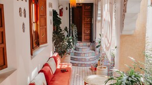 A cozy interior with a red sofa, a patterned floor, and a wooden door. - Riad TOYOUR (Fes)