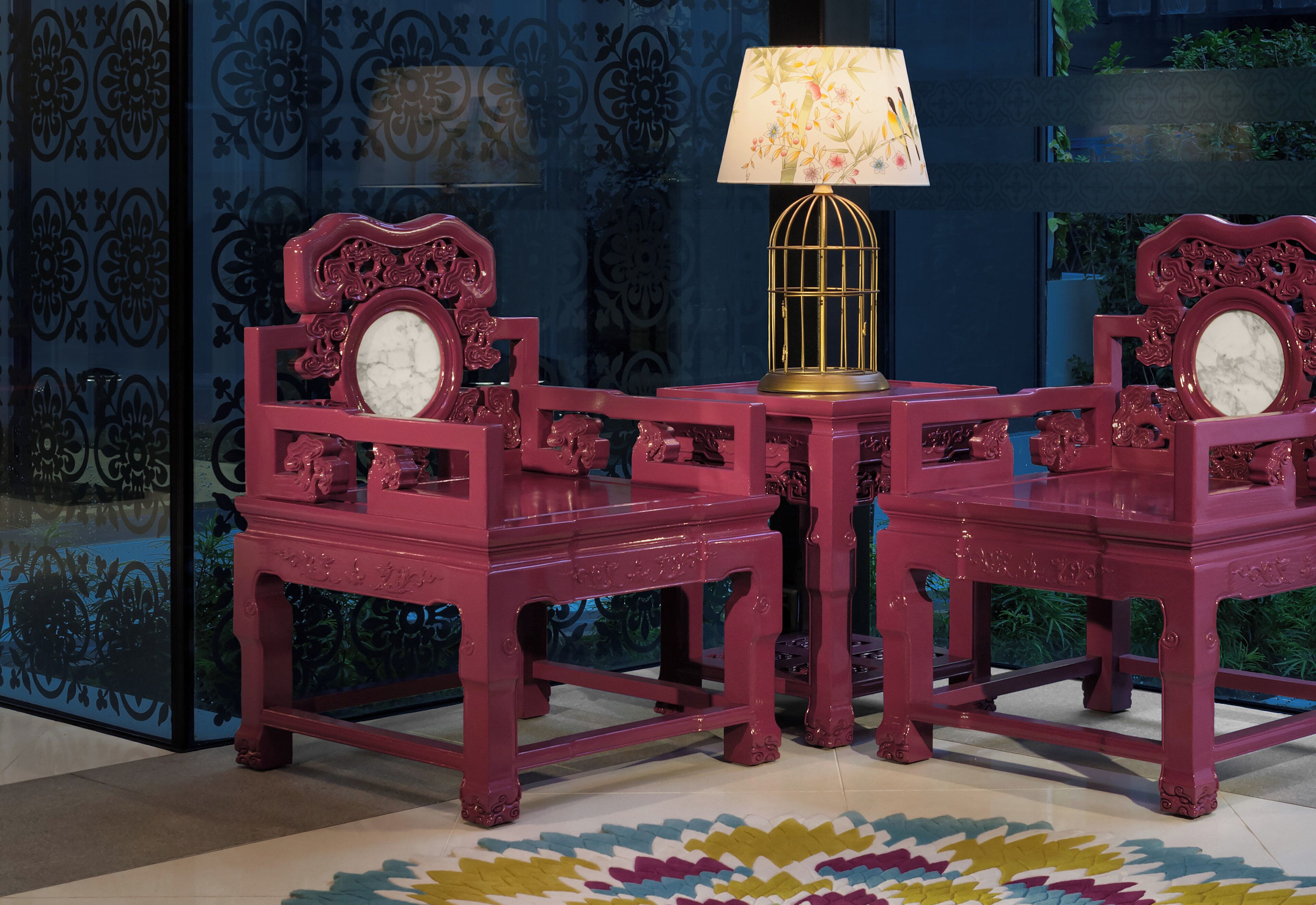 Una habitación con piso estampado, una mesa con lámpara y dos sillas de diseño elaborado.