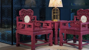 Una habitación con piso estampado, una mesa con lámpara y dos sillas de diseño elaborado.