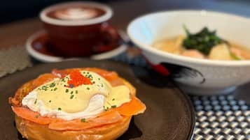 A breakfast setting with a poached egg on toast, salmon, and a bowl of soup.