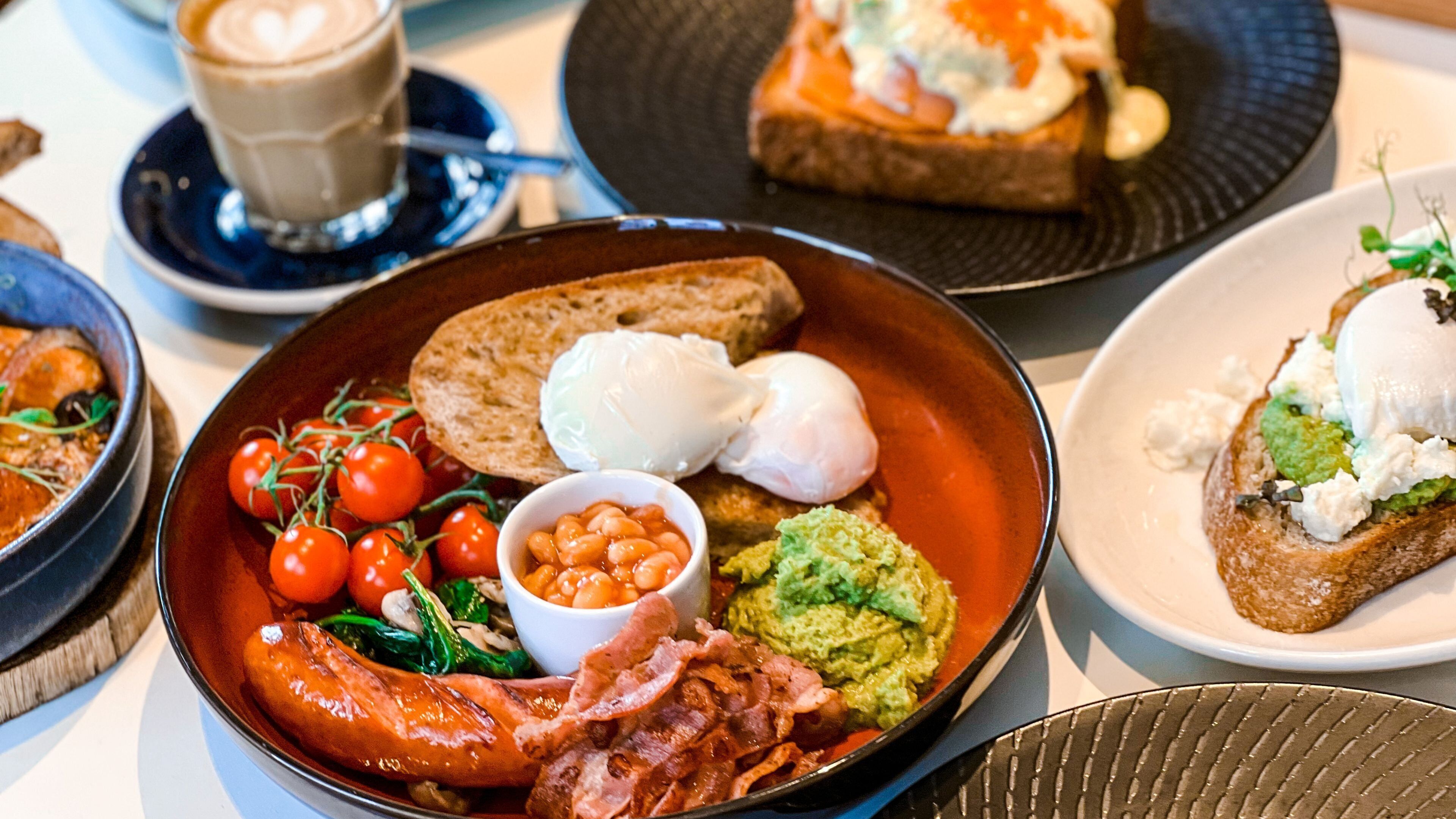 Ein reichhaltiges Frühstücksbuffet mit verschiedenen Speisen, darunter Eier, Toast, Bohnen, Speck und Tomaten.