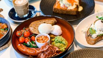 Ein reichhaltiges Frühstücksbuffet mit verschiedenen Speisen, darunter Eier, Toast, Bohnen, Speck und Tomaten.