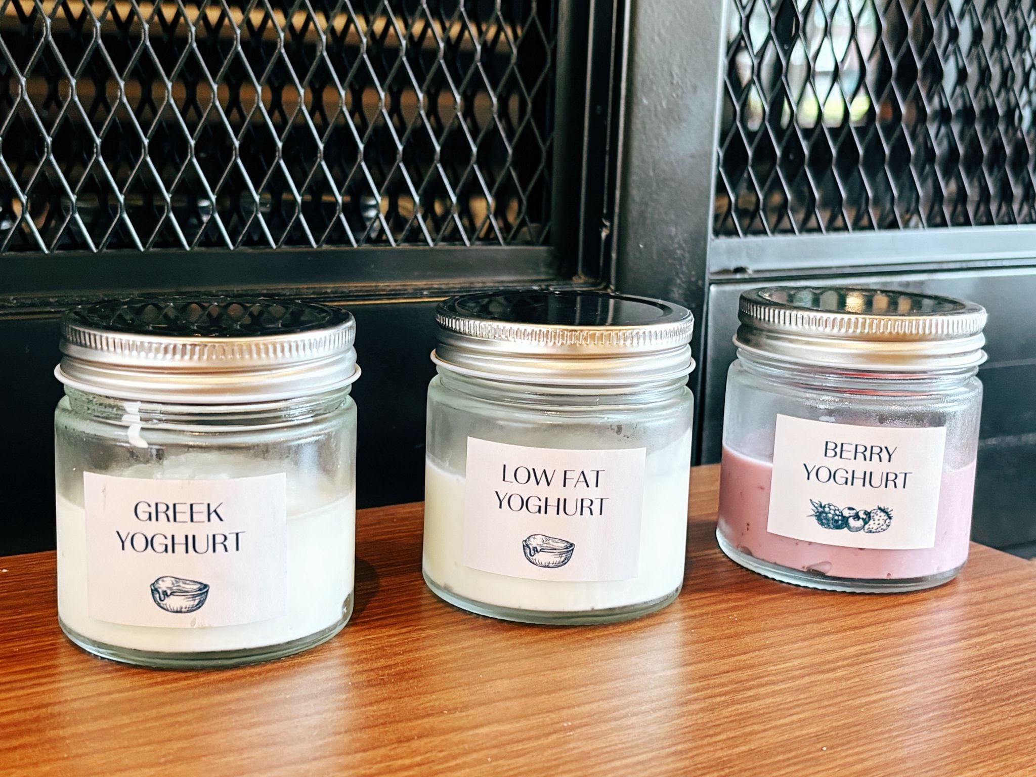 Three glass jars with labels on a wooden surface.