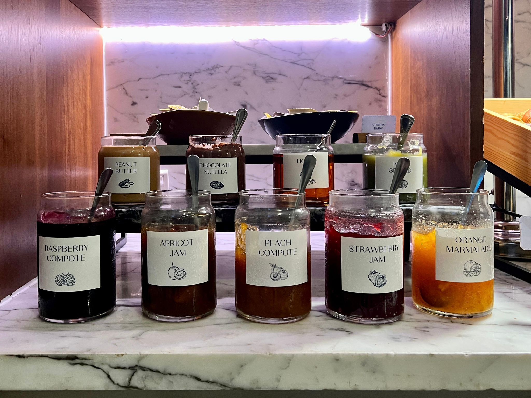 A selection of jars containing various jams and spreads on a marble countertop.