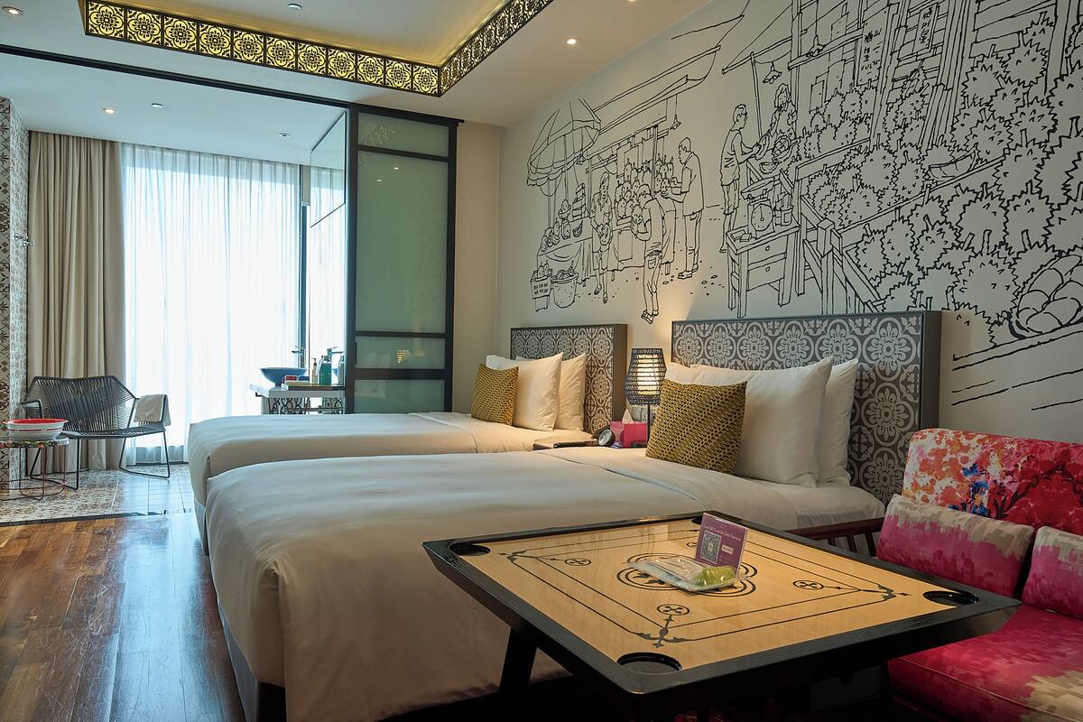 A hotel room with two beds, a coffee table, a sofa, and a dining table.