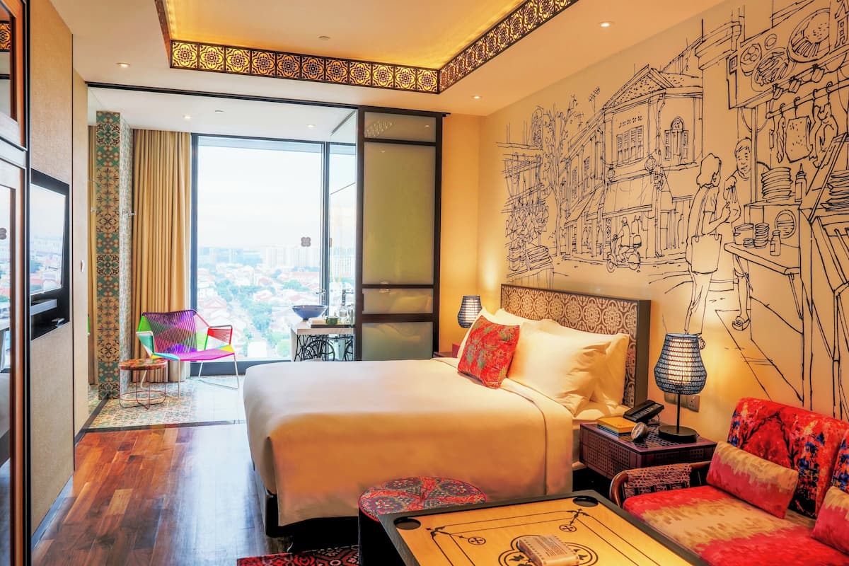 A hotel room with a large bed, a sofa, a desk, and a view of the city.