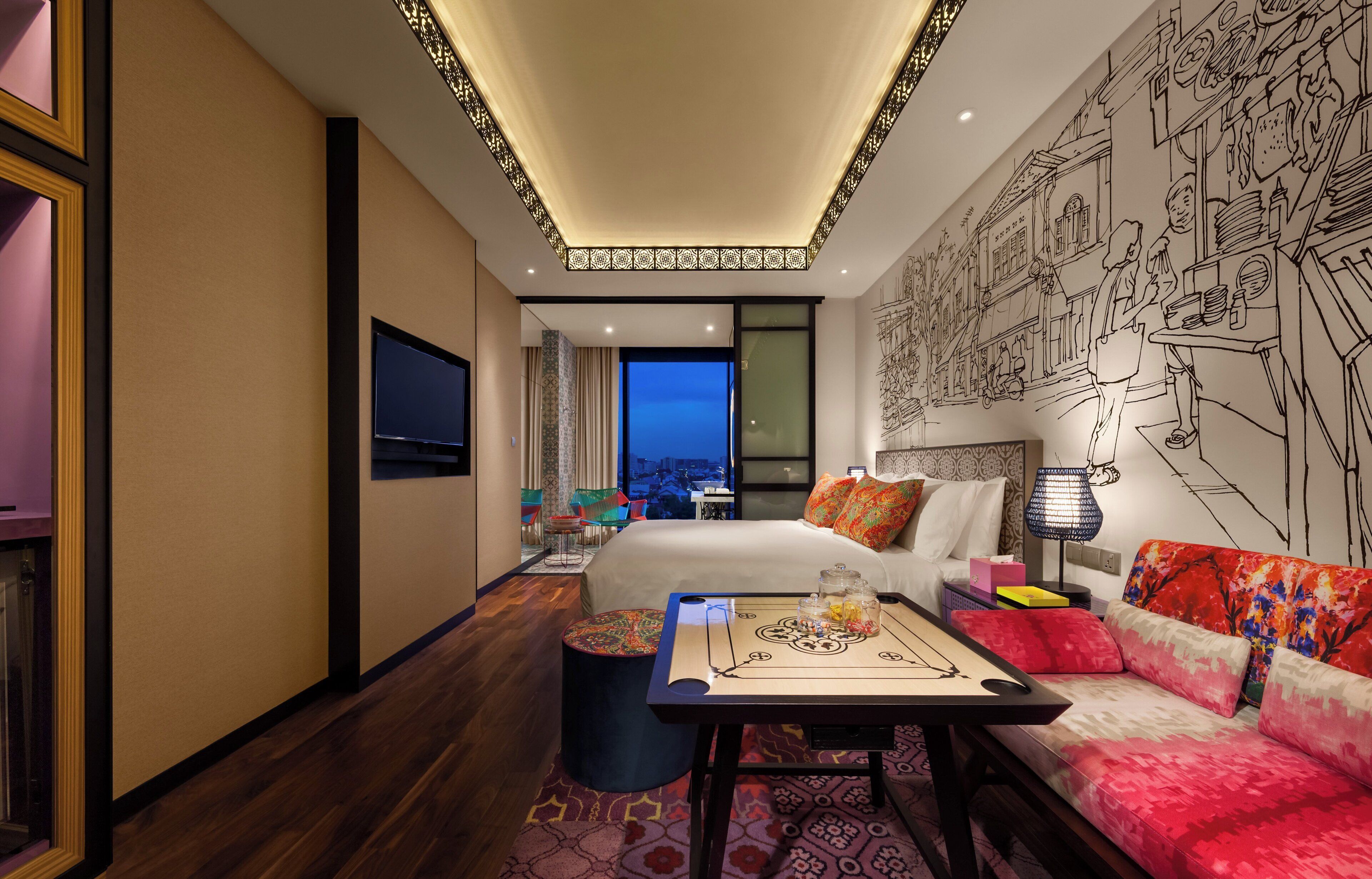 A hotel room with a bed, a sofa, a table with items, a TV, and a cityscape view.