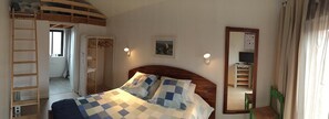 A bedroom with a bed, a wooden ladder, a wardrobe, a mirror, and a window. - Hotel du Cap (Lège-Cap-Ferret)