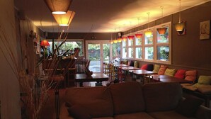 A restaurant interior with a long counter, multiple tables, and a seating area with cushions. - Hotel du Cap (Lège-Cap-Ferret)