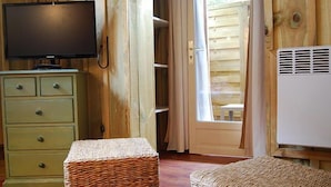 A room with a television on a dresser, a wicker basket, and a white air conditioning unit. - Hotel du Cap (Lège-Cap-Ferret)