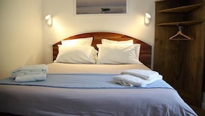 A neatly made bed with white linens and towels, a wooden headboard, and a painting above the bed. - Hotel du Cap (Lège-Cap-Ferret)