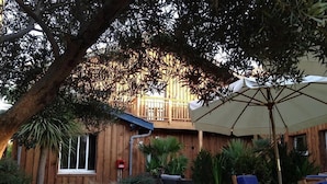 A wooden deck with outdoor furniture, a covered seating area, and a wooden fence. - Hotel du Cap (Lège-Cap-Ferret)