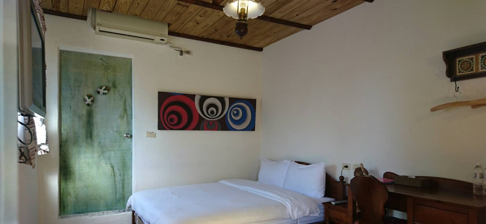 A room with a bed, a desk, and a wall-mounted air conditioner.