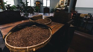 A room with a wooden table filled with coffee beans, wicker baskets, and a wooden chair. - Monet Garden B&B (Shoufeng)