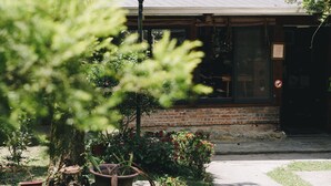 A building with a brick facade, a wooden porch, and a small garden with a pond. - Monet Garden B&B (Shoufeng)
