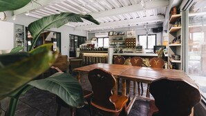A spacious dining area with a wooden table and chairs, surrounded by shelves and a kitchen area. - Monet Garden B&B (Shoufeng)