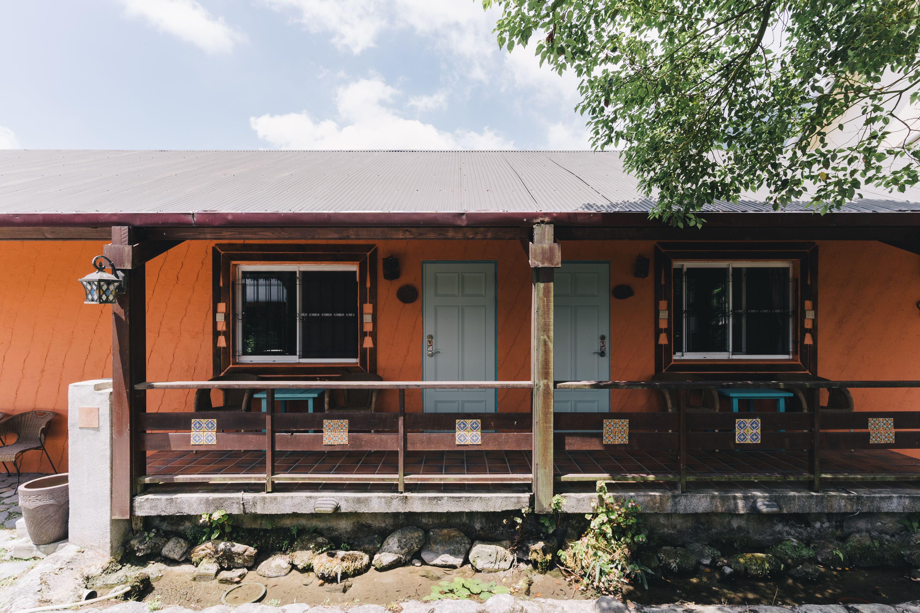 A building with a tiled porch, two doors, and a window.