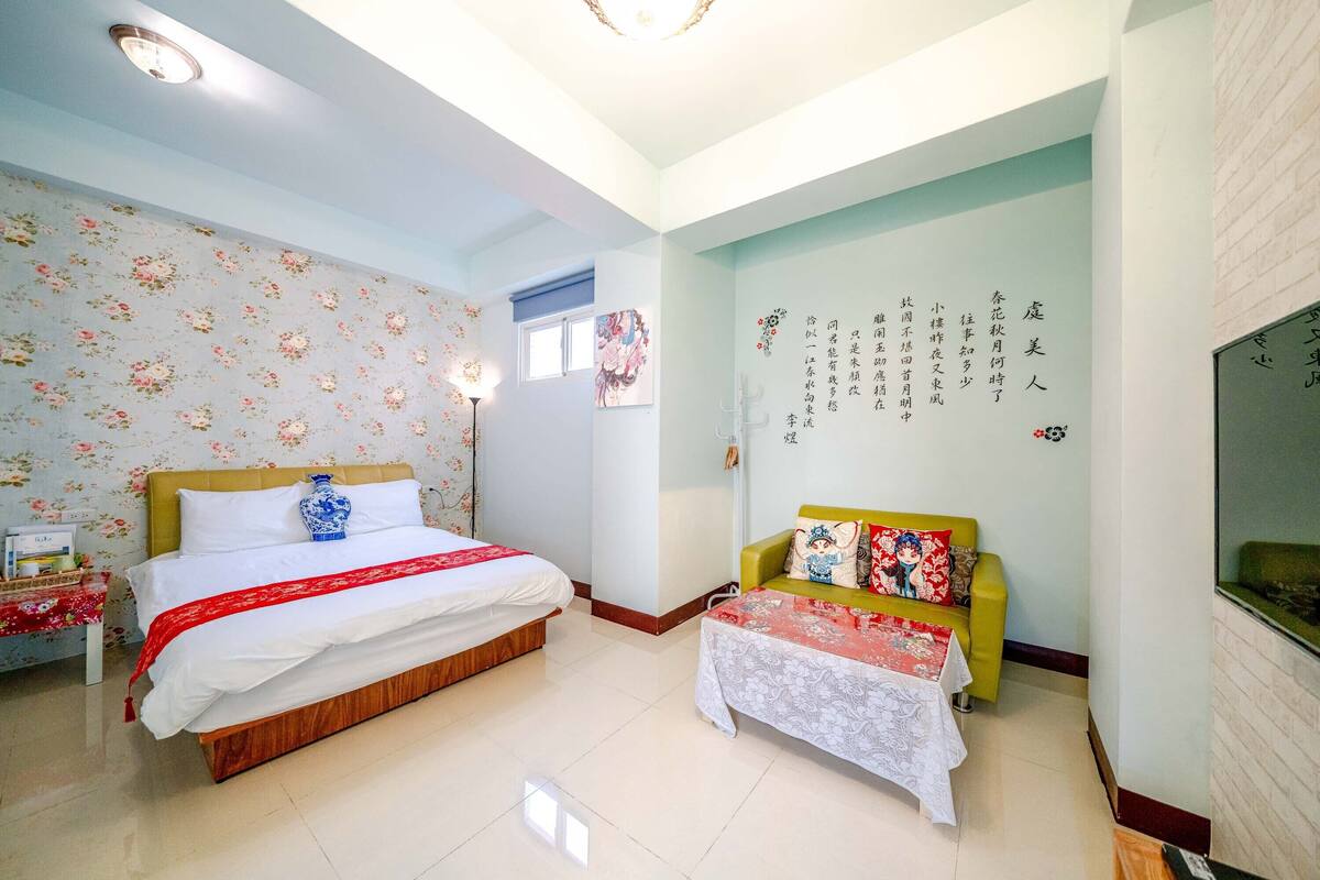 A hotel room with a large bed, a sofa, and a wall with decorative writing.