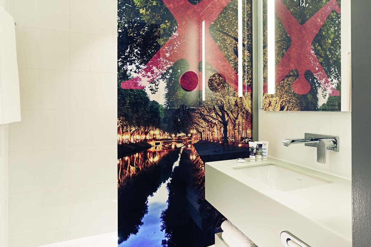 Ein Badezimmer mit einem weißen Waschbecken, einem Spiegel und einem Handtuchhalter an der Wand.