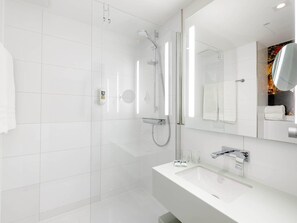 Une salle de bain moderne avec une douche à parois de verre, un lavabo blanc et un grand miroir.