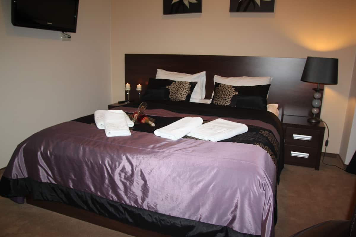 Una cama bien hecha con una colcha morada, toallas blancas y almohadas decorativas.