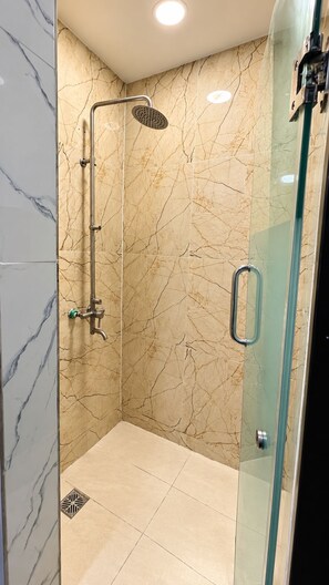 A glass-enclosed shower with a handheld showerhead and a wall-mounted faucet. - Residency Hotel Lekki Lagos (Lekki)